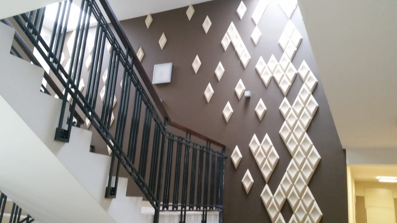 Schody wewnętrzne z metalową balustradą i nowoczesnymi elementami dekoracyjnymi na ścianie.