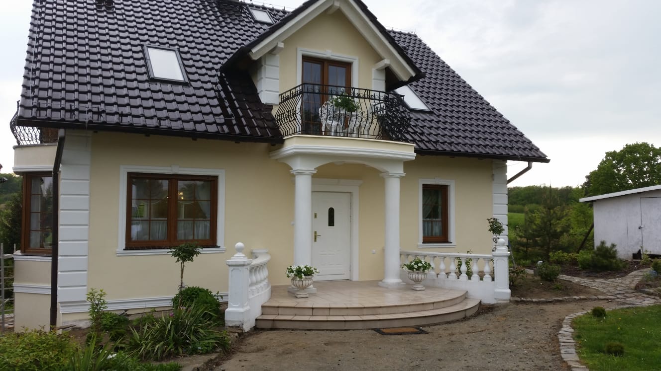 Realizacja sztukaterii zewnętrznej Wrocław - Dom jednorodzinny z kolumnami i gzymsami na fasadzie oraz balkonem na piętrze.
